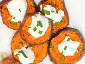 5 Roast Sweet Potato Slices on a white plate with a dollop of sour cream and chive garnish.