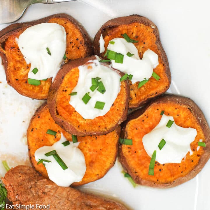 5 Roast Sweet Potato Slices on a white plate with a dollop of sour cream and chive garnish.