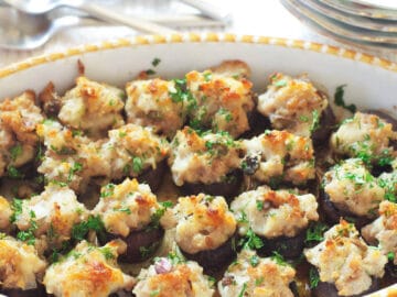 Sausage & Cheese Stuffed Mushrooms in Yellow & White Baking Pan with a parsley garnish.