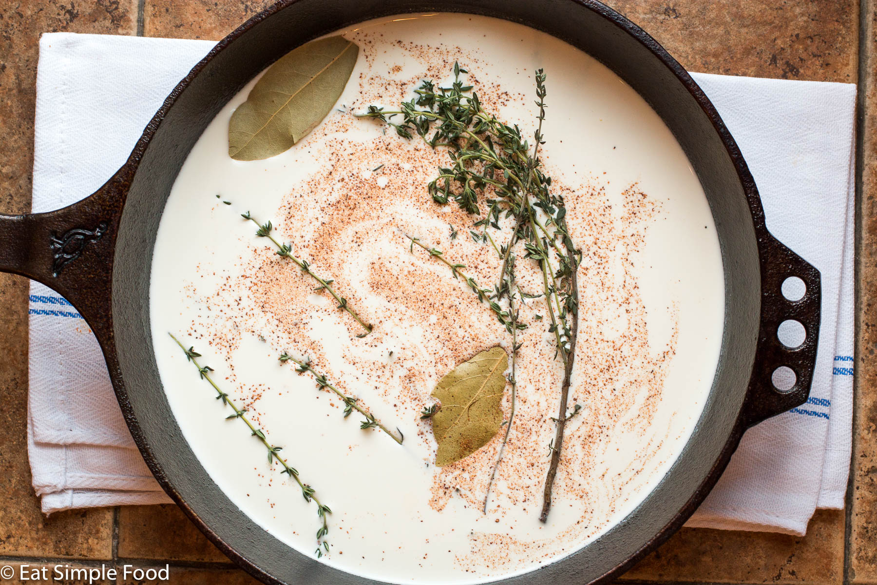 Cream, nutmeg, bay leaves, and thyme in heavy whipping cream in a cast iron skillet.