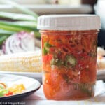 Mason Jar with White Lid of Preserved Sliced Red, Orange, & Yellow Shishito Peppers