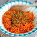 Grated Carrots, Raisins, toasted Walnuts, and sliced Mint Salad in a white bowl with a blue rim.