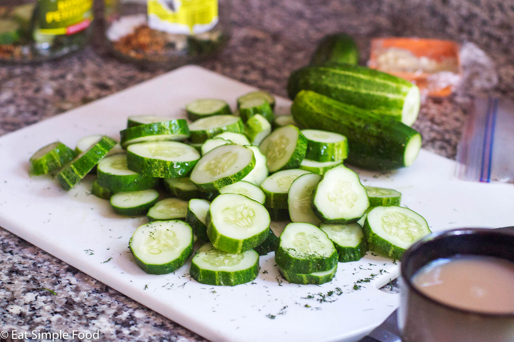 Sliced pickling cucumbers on a white cutting board