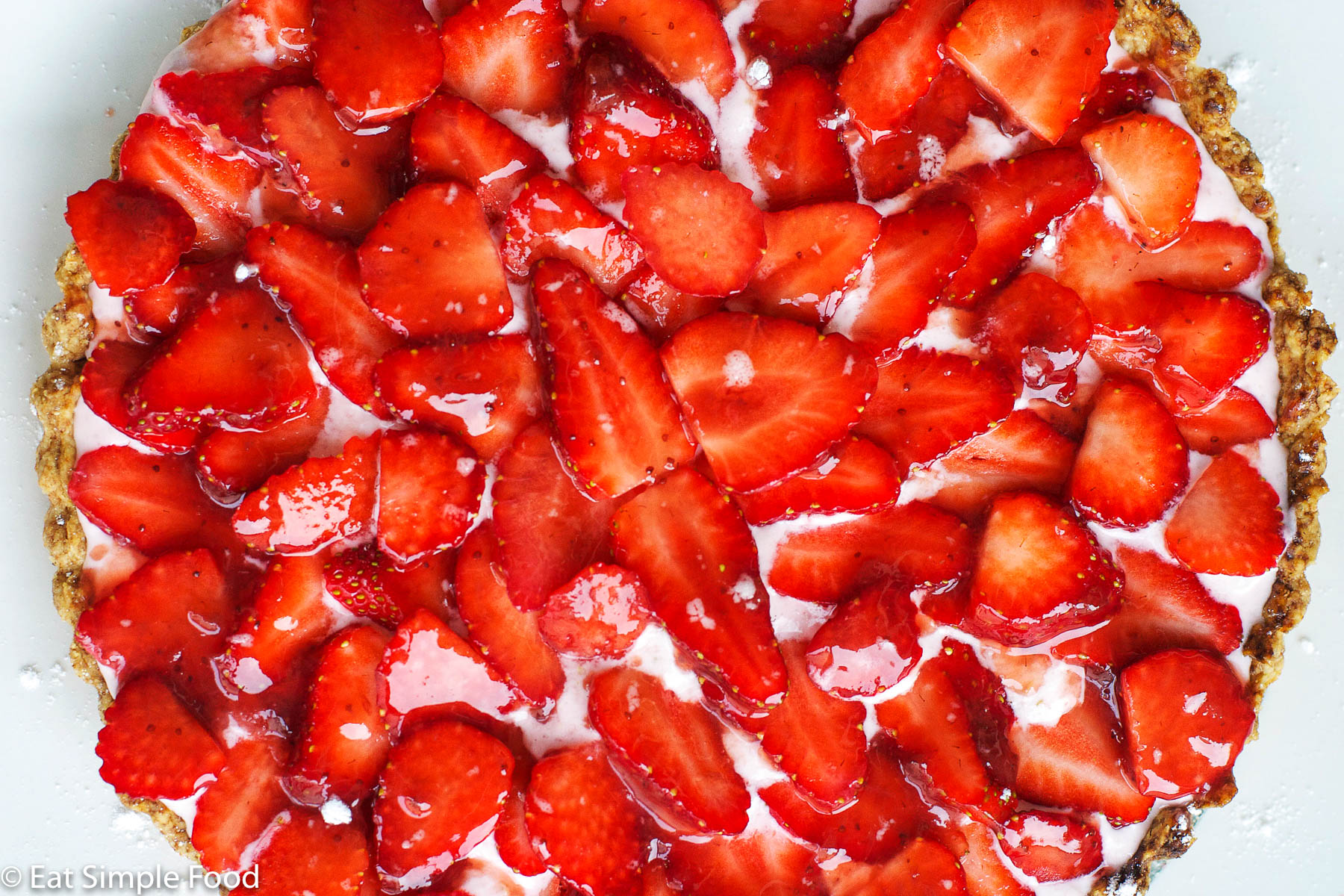 Top view of fresh sliced strawberry over a pink cream filling of a crispy tart.