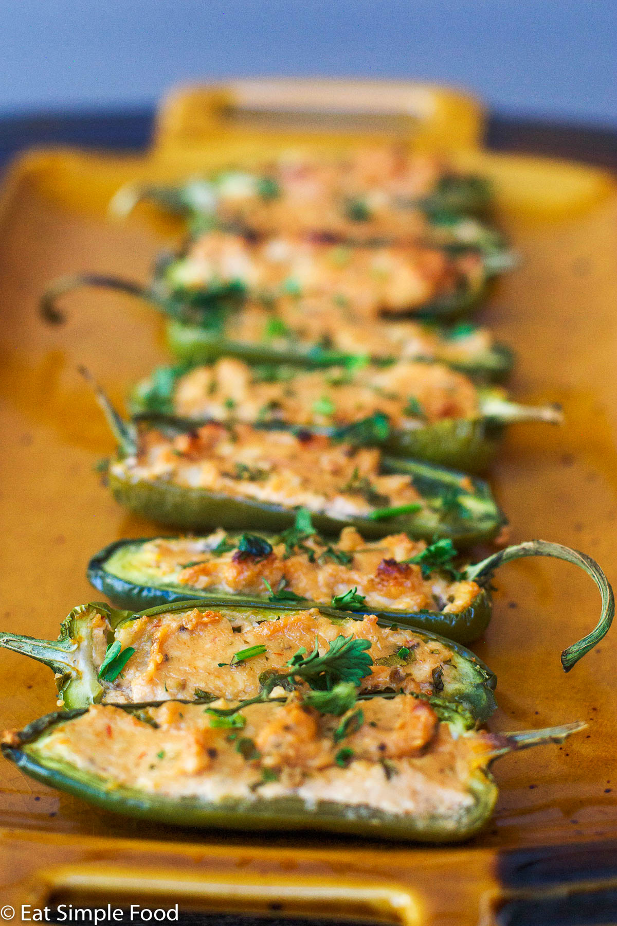 Baked & Stuffed Jalapeno Popper halves on a tan plate filled garnished with parsley | EatSimpleFood.com
