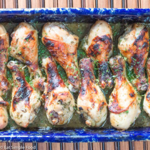 Close up of Brown Roasted Chicken legs in a cilantro sauce in a blue baking dish.