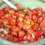 Close up of fresh diced tomatoes, jalapenos, red onions, cilantro in a bowl.