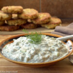Bowl of Tzatziki (yogurt, cucumbers, lemon) sauce. falafels in background.