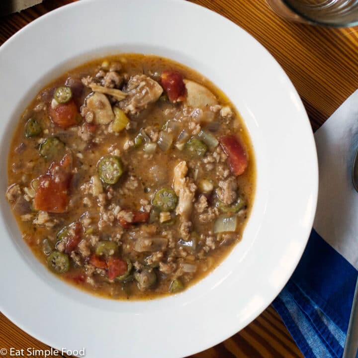 Chicken & Sausage Gumbo in a white shallow bowl with sliced okra.