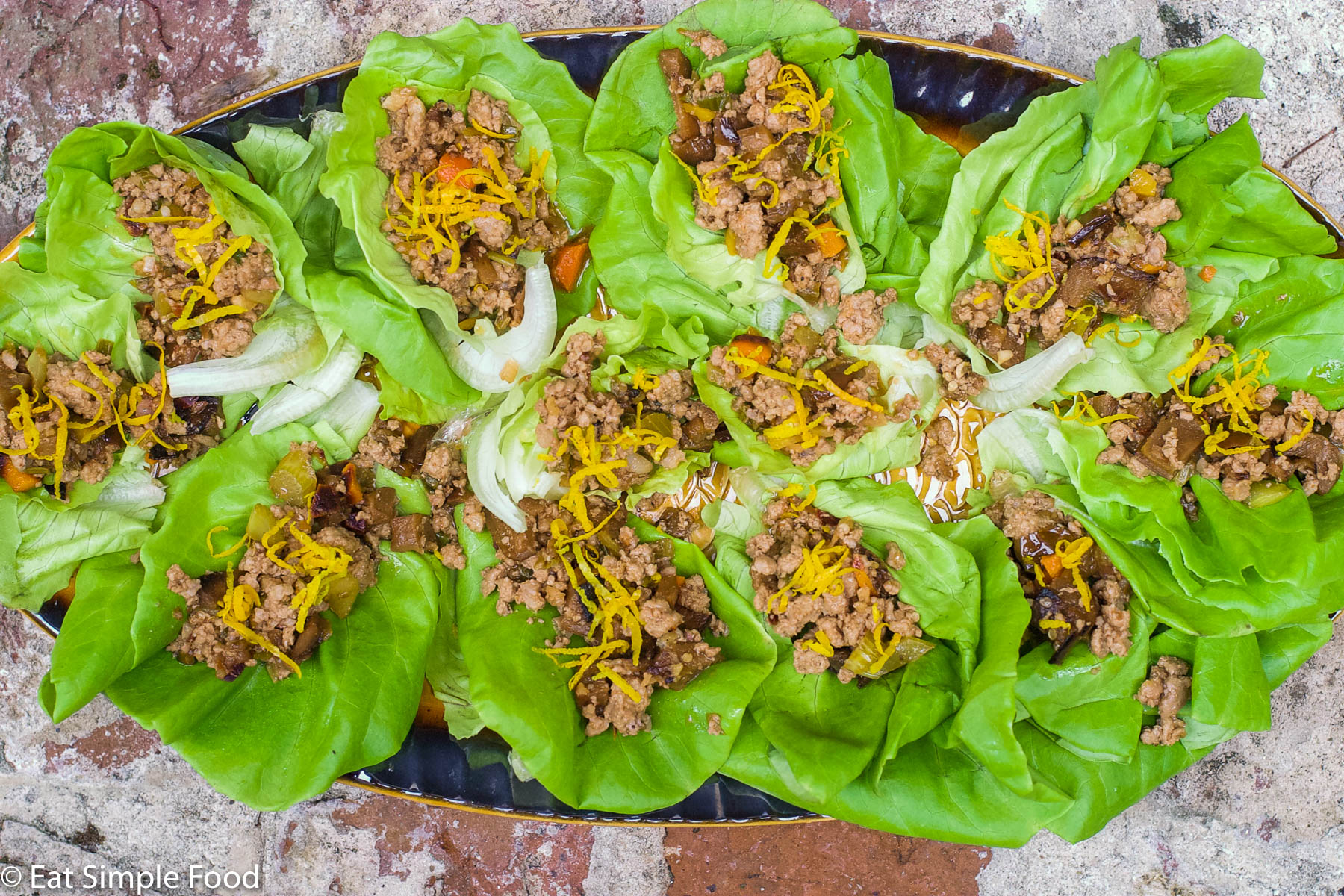 Close Up of Sauteed ground pork and veggies stuffed in a lettuce wrap and topped with orange zest. Top view.