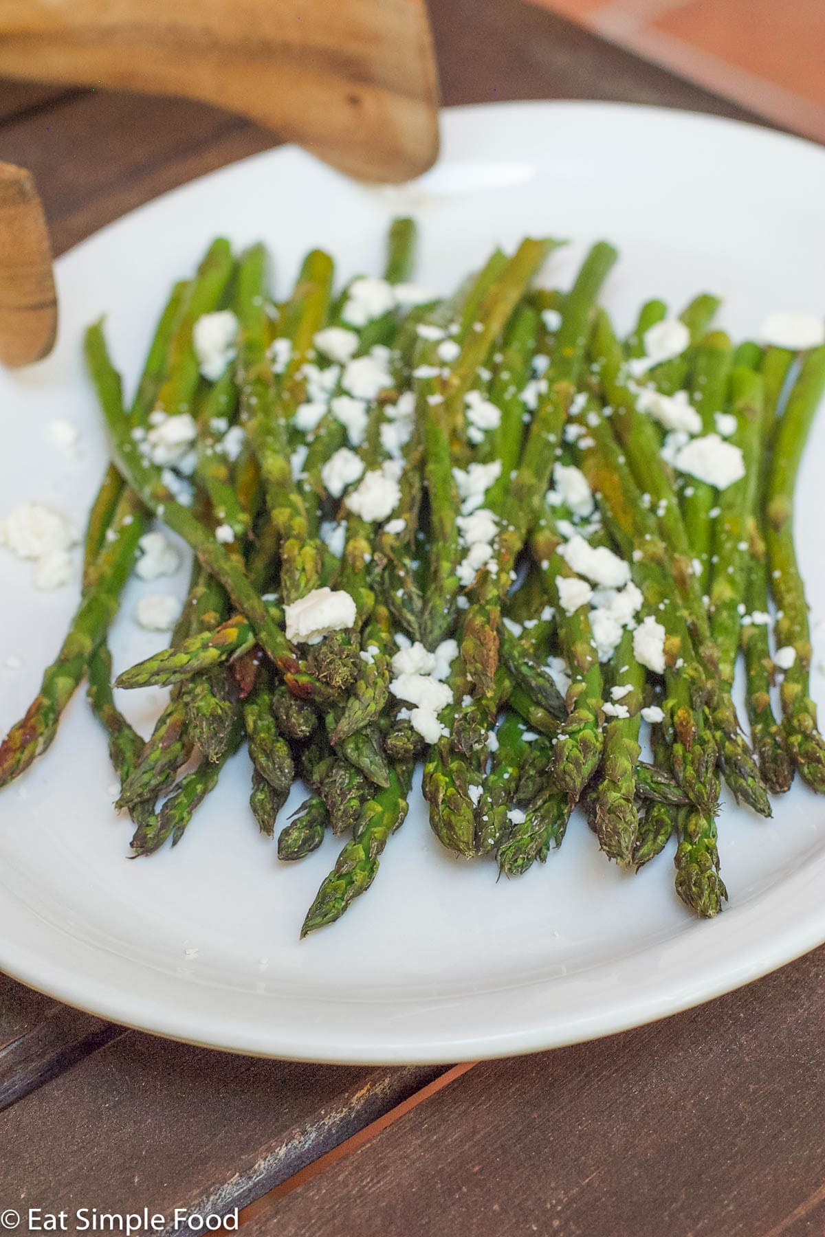 Roasted Asparagus with Feta garnish on a white plate with a black rim. side view with spear heads facing forward.