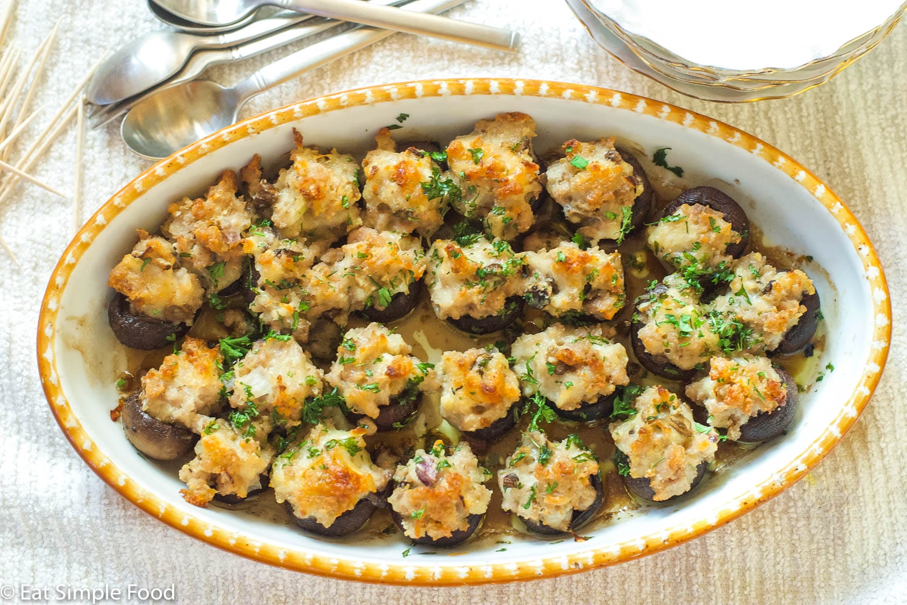 Sausage & Cheese Stuffed Mushrooms in Yellow & White Baking Pan with a parsley garnish. Top View.