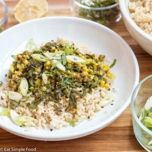 White plate of Yellow/ Green Mung Beans (Lentils), over brown rice, garnished with red pepper flakes and green onions.