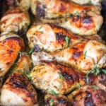 Brown Roasted Chicken legs in a cilantro sauce in a blue baking dish. Close up. Side view.