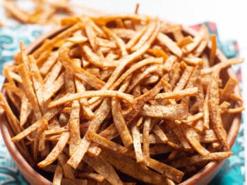 Close up of crispy baked tortilla chips in a wood bowl. Side view.