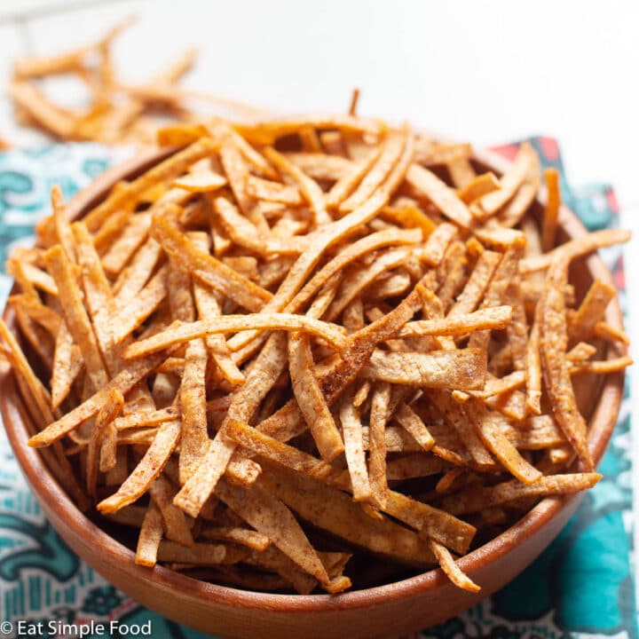 Close up of crispy baked tortilla chips in a wood bowl. Side view.