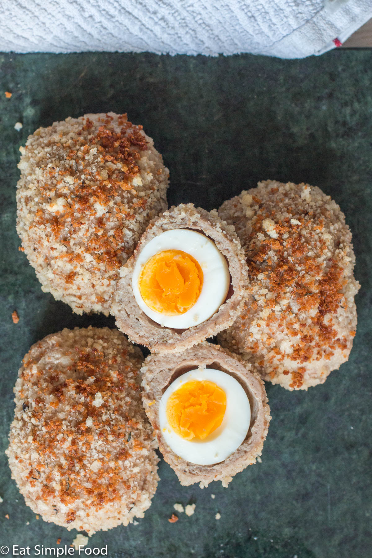 Top view of a cut open turkey scotch egg revealing a the egg and the egg yolk wrapped in cooked turkey and breadcrumbs.
