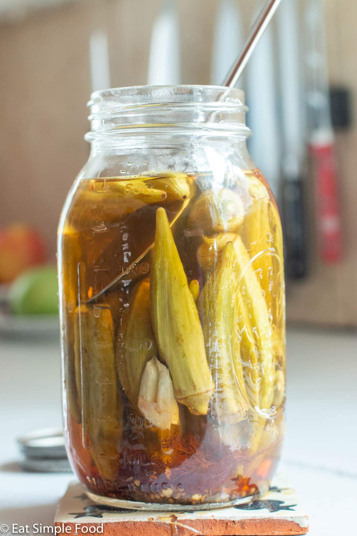 Mason quart jar filled with whole okra, garlic cloves, and brine.