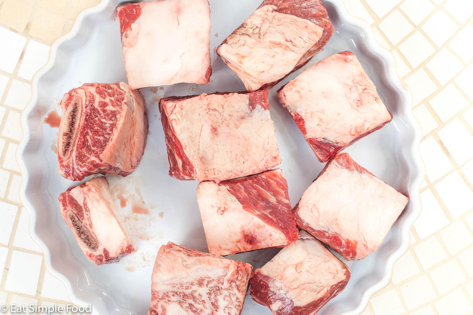 Raw Ribs in a round white baking dish with the fat side up.