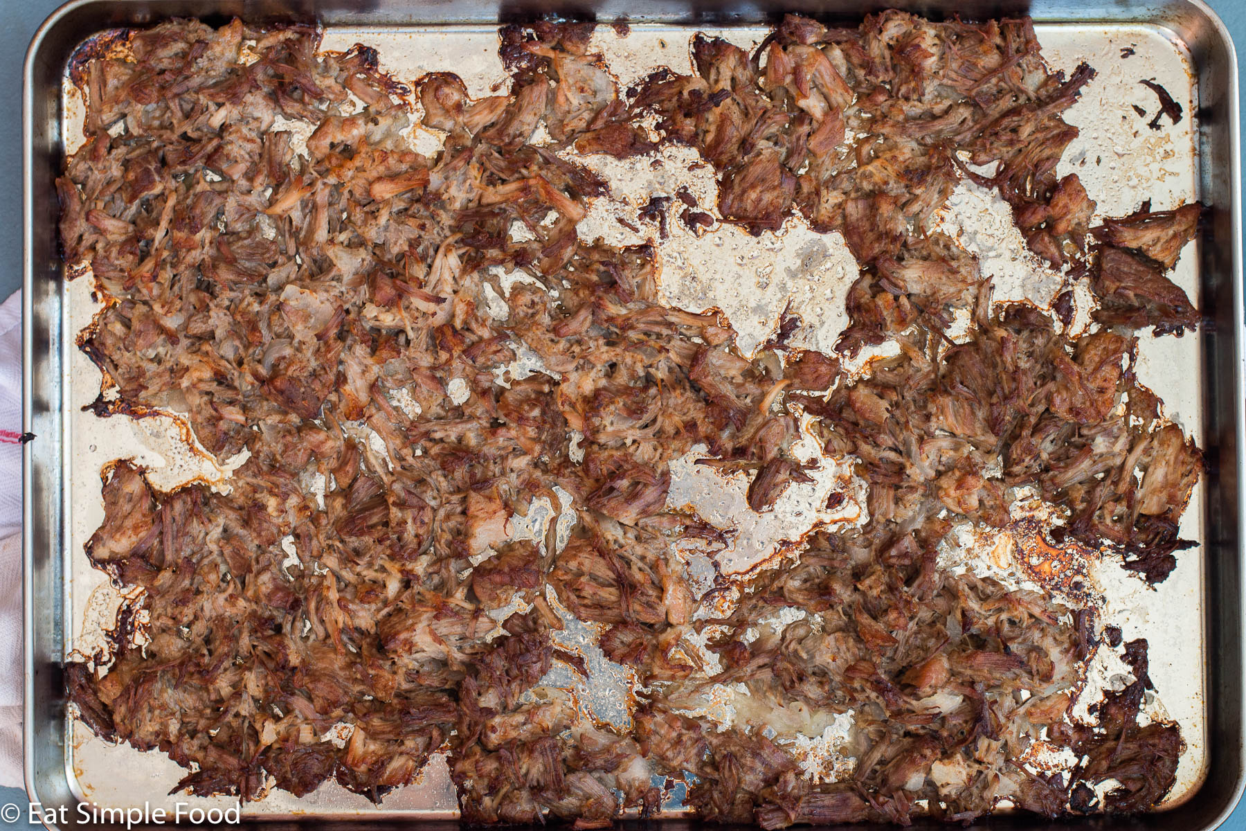 Top view of crispy shredded pork carnitas on a sheet pan.