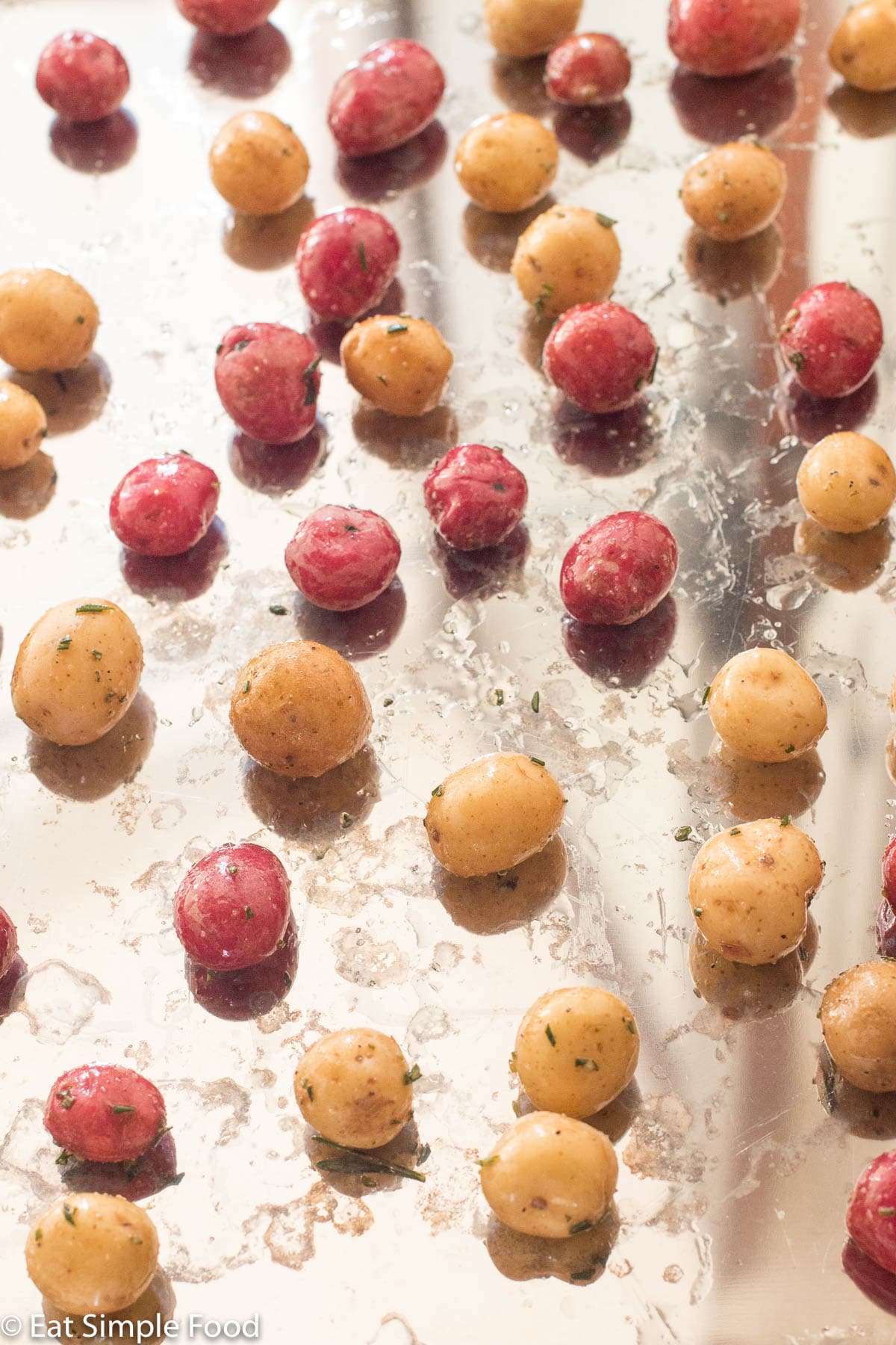 Raw colorful baby potatoes on a silver baking sheet.