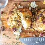 Roasted cauliflower half face down sprinkled with cranberries, pistachios, and chopped rosemary.