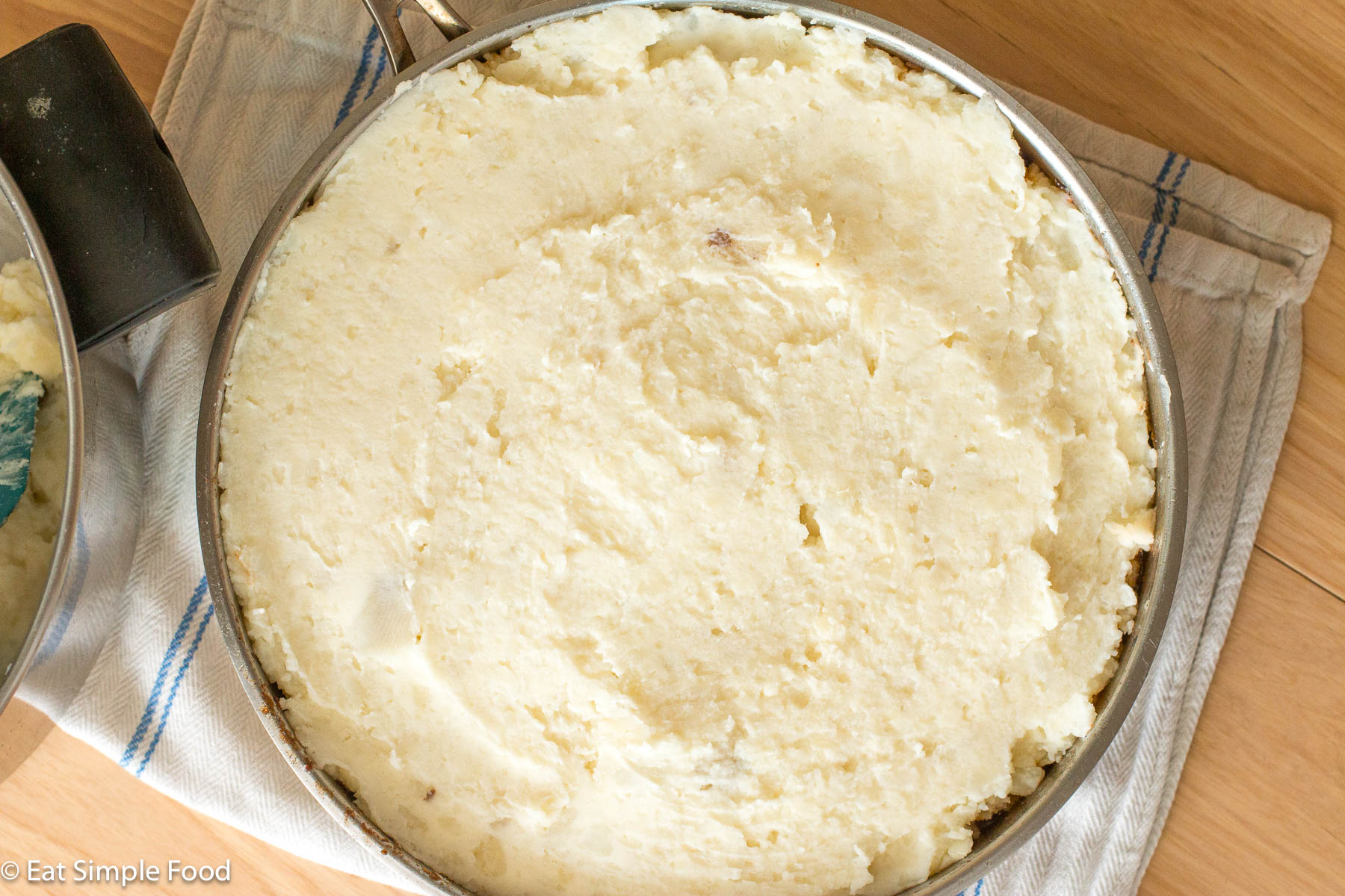 Top down view of a stainless steel pan filled with white mashed potatoes.