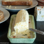 Close up of butter in a green butter dish with toast in the background.