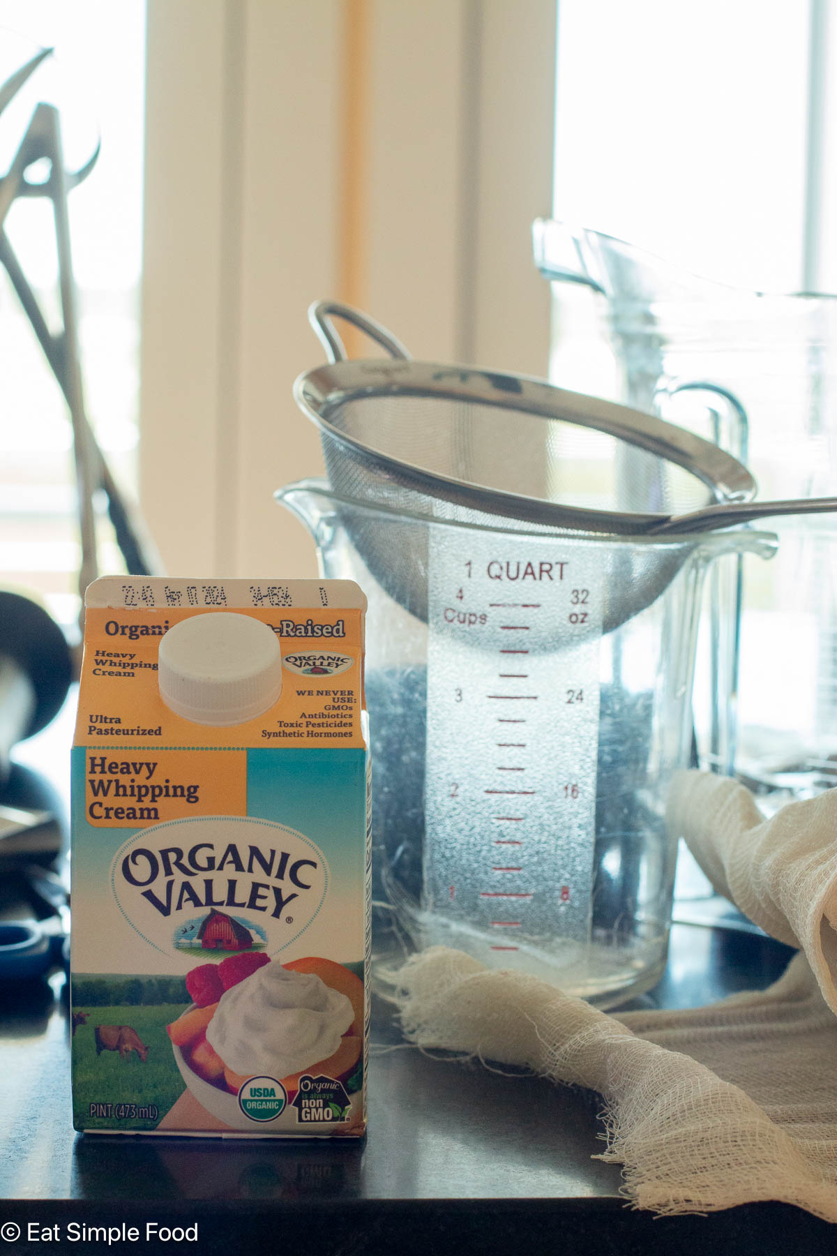 Yellow food box container in front of a 4 cup measuring cup with a strainer on top.