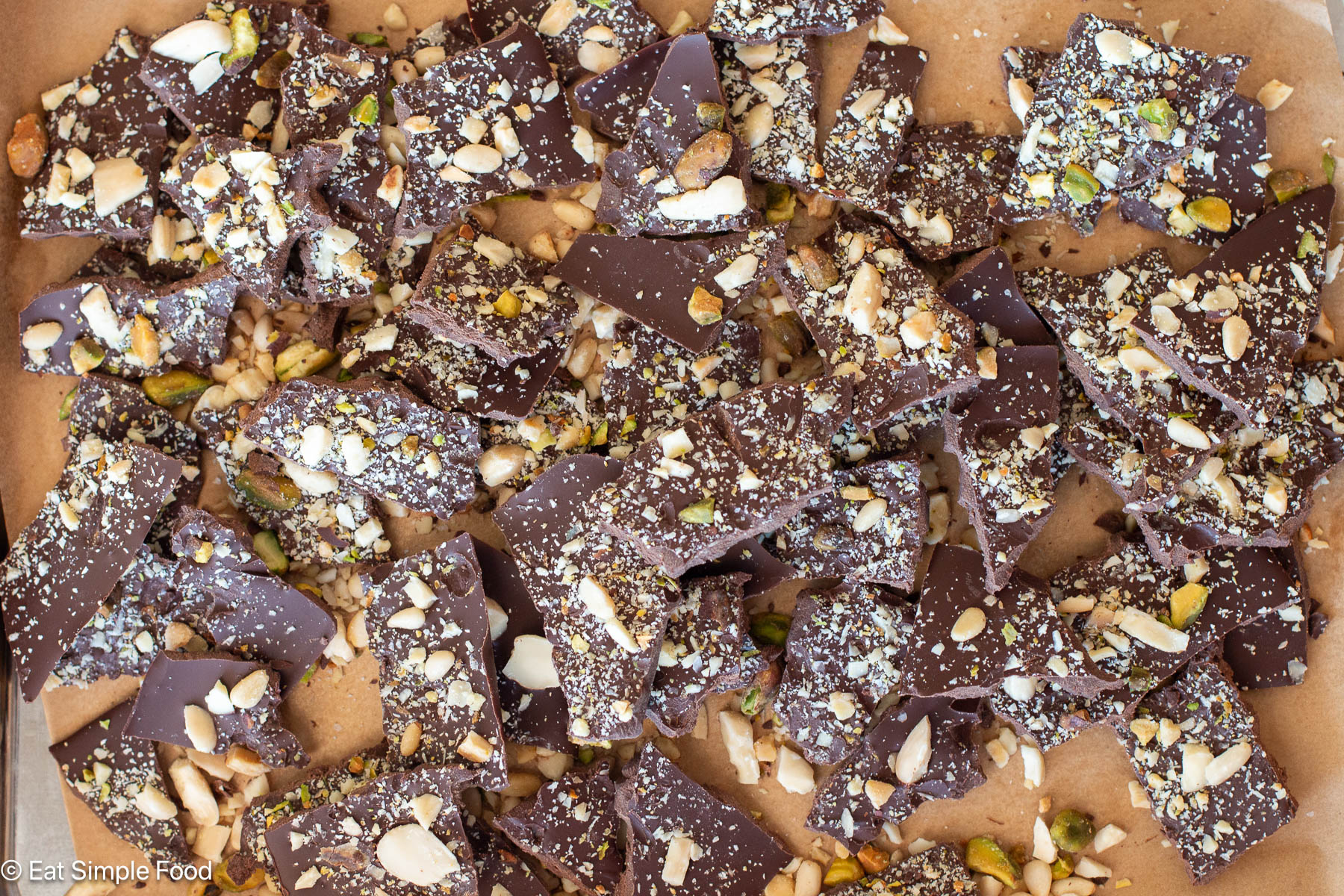 Top down view of broken pieces of dark cholate with chopped nuts.