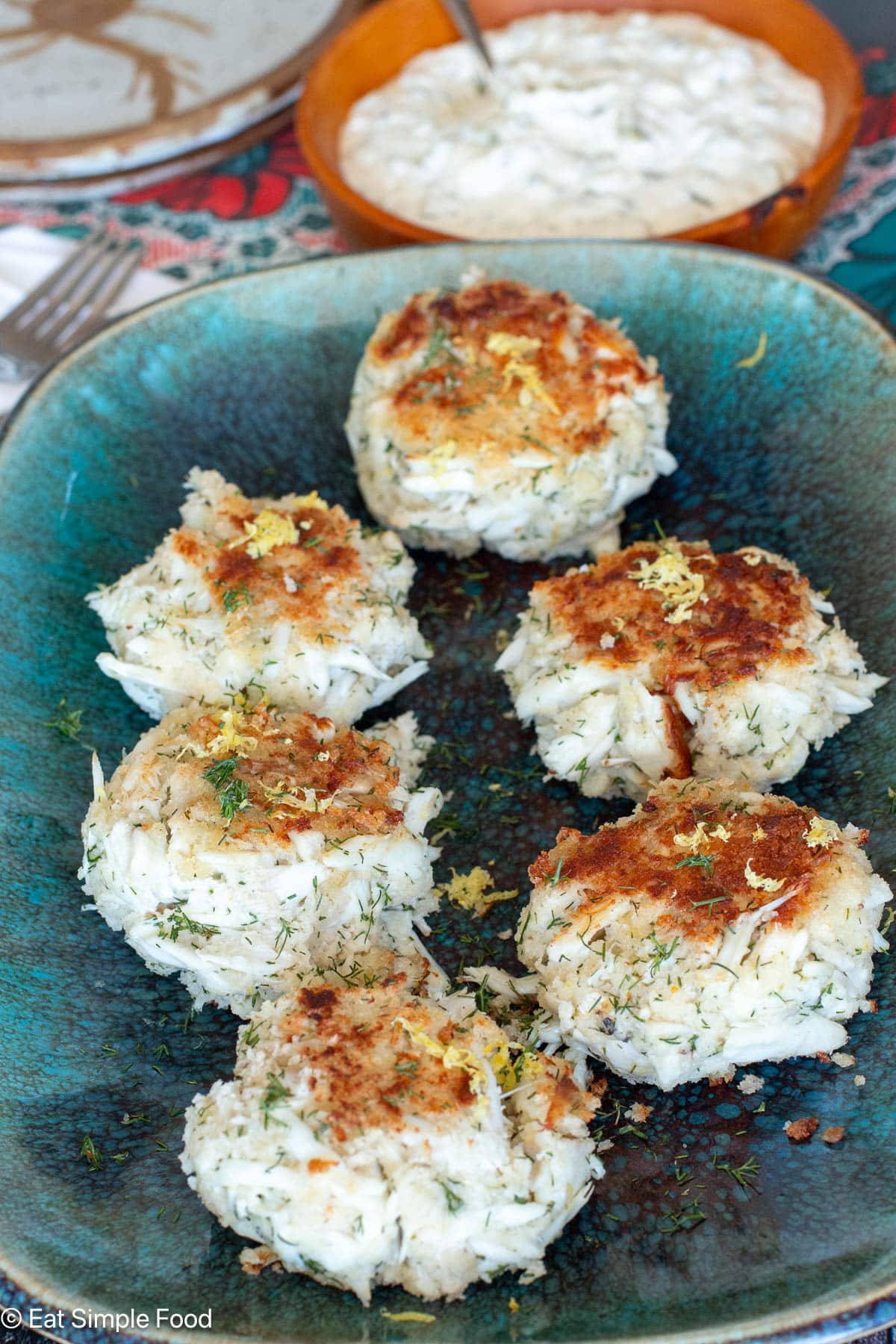 Side view of seared crab cakes on an aqua rectangle plate.