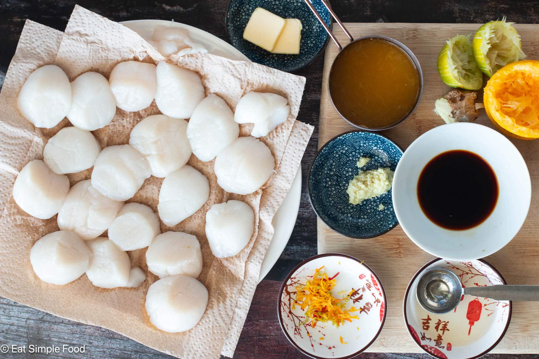 Ingredients: plate of raw scallops on paper towels, individual bowls of ginger zest, citrus zest, orange juice, butter tabs, soy sauce, and ginger.