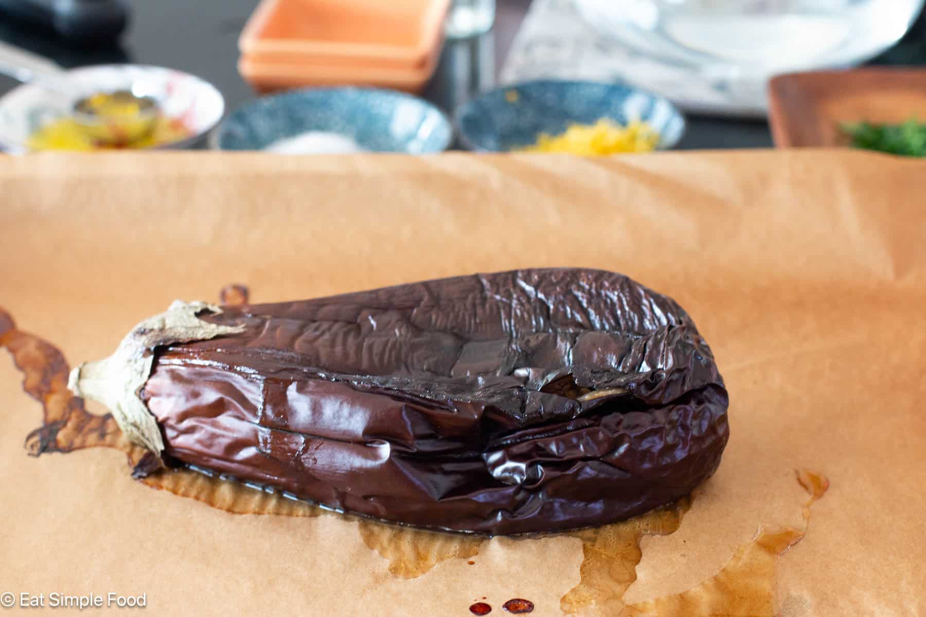 Collapsed cooked purple eggplant on a piece of parchment paper.