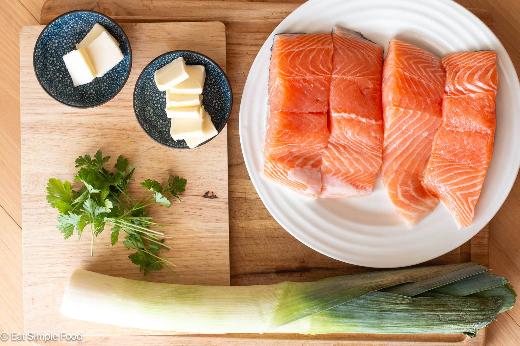 Raw ingredients: parsley, butter tabs, big leek, and plate of 4 pieces of raw salmon.