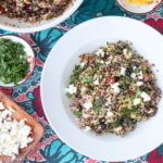 Top down view of grain salad with feta cheese on a colorful table runner.