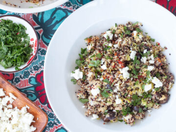Top down view of grain salad with feta cheese on a colorful table runner.