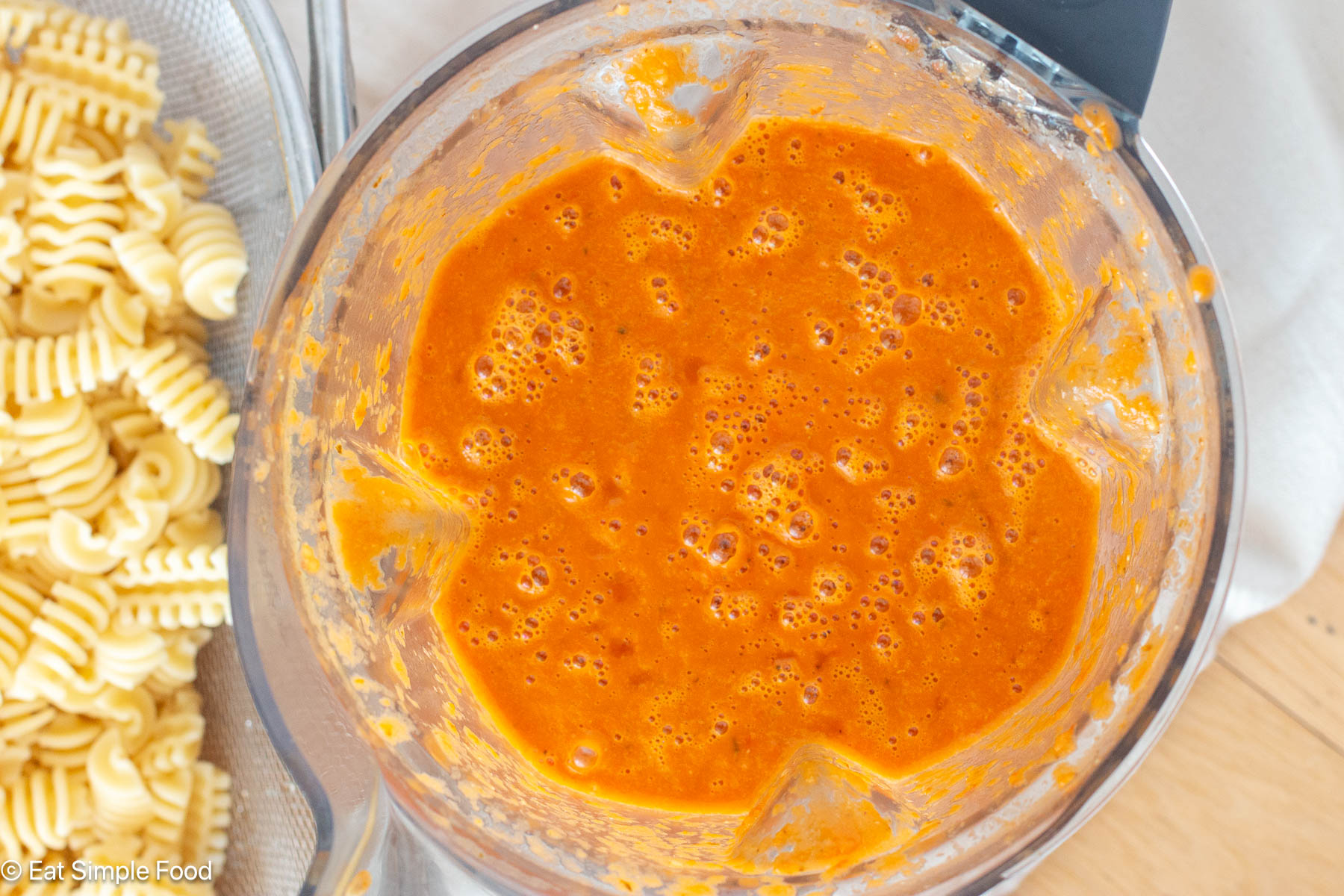 Pureed red sauce in a blender with pasta sauce on the side.